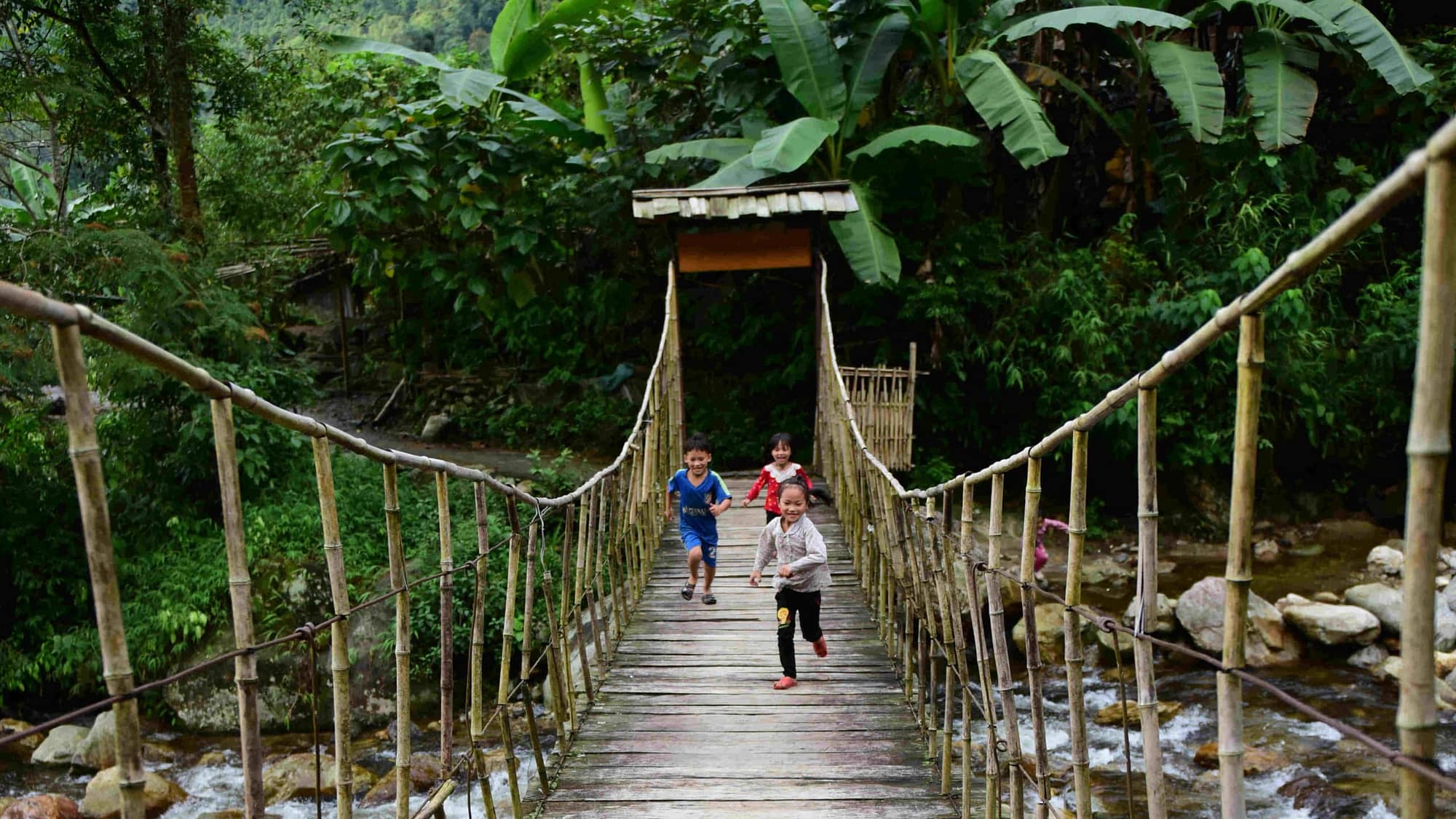 Go Indochine Kinder spielen auf Hängebrücke Vietnam